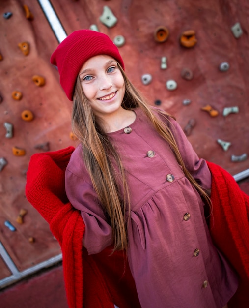 Bambina felice in posa accanto a una parete da arrampicata