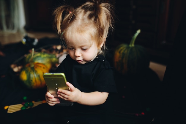 Bambina guardando un telefono intelligente con uno sfondo zucca