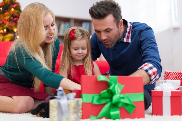 Bambina impaziente che apre i regali di Natale con i genitori