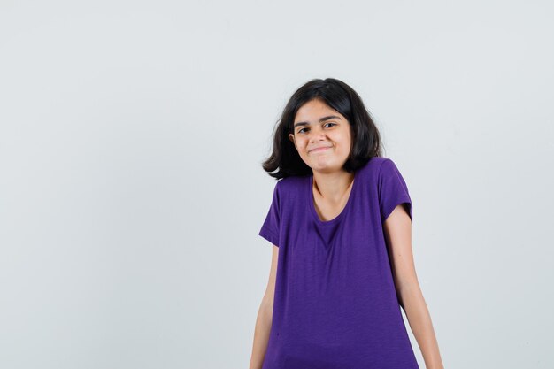 Bambina in maglietta che scrolla le spalle e sembra allegra,
