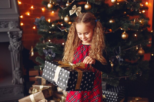 Bambina in piedi vicino all'albero di Natale con il presente