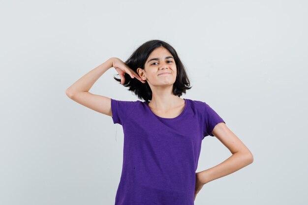 Bambina in posa mentre tocca i capelli in maglietta e sembra bello