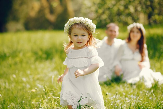 Bambina in un campo in erba con i suoi genitori