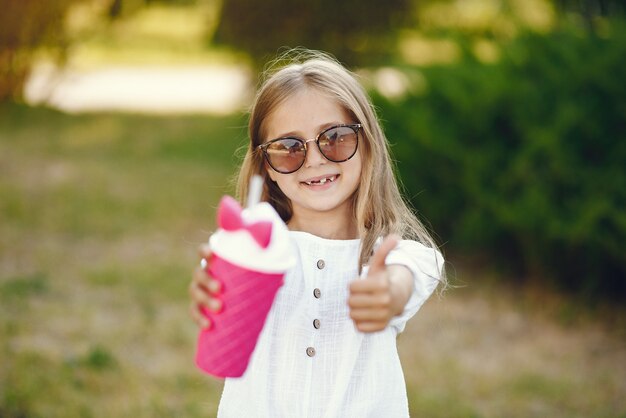 Bambina in un parco che sta con la tazza rosa
