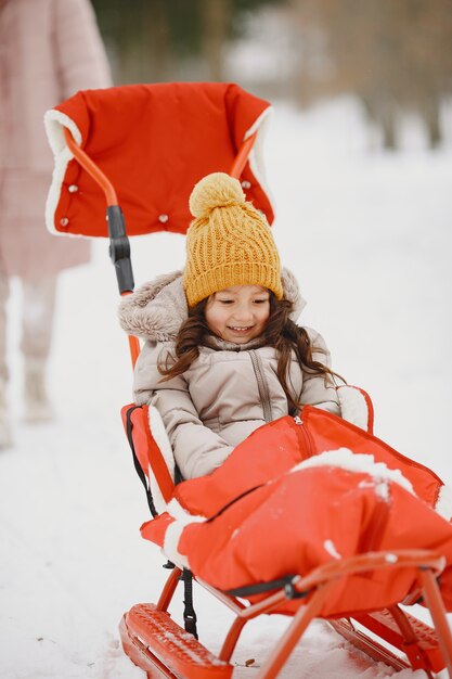 Bambina in una slitta sul parco innevato