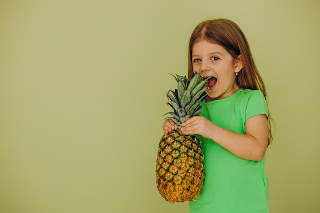 Bambina isolata che tiene ananas