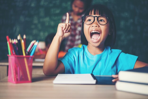 Bambina premurosa con il libro vicino a un consiglio scolastico