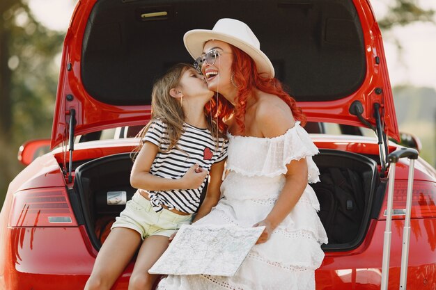 Bambina pronta per andare in vacanza. Madre con la figlia che esamina una mappa. Viaggiare in macchina con i bambini.