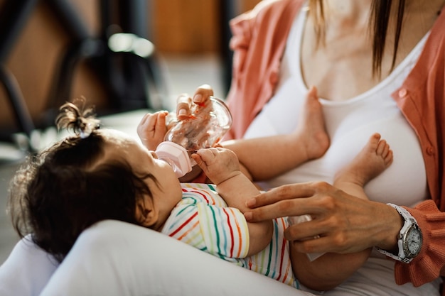 Bambina sdraiata in grembo alla madre e acqua potabile forma biberon