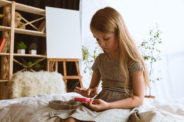 Bambina seduta nella sua stanza con smartphone e giochi
