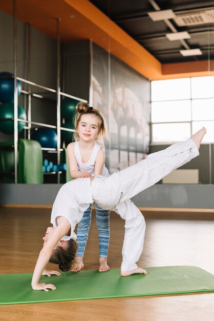 Bambina sorridente che aiuta sua sorella a esercitarsi in palestra