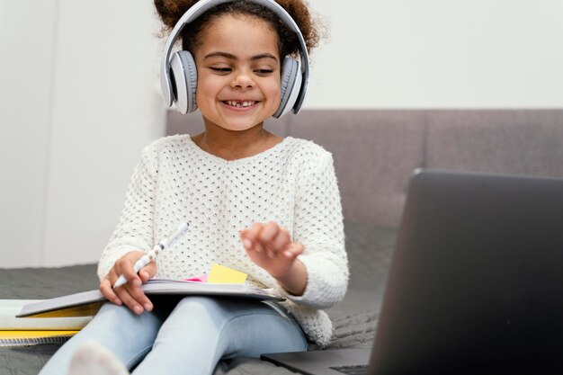 Bambina sorridente che utilizza computer portatile per la scuola in linea
