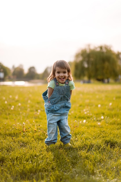 Bambina su un campo di tarassaco, al tramonto, bambino felice emotivo.