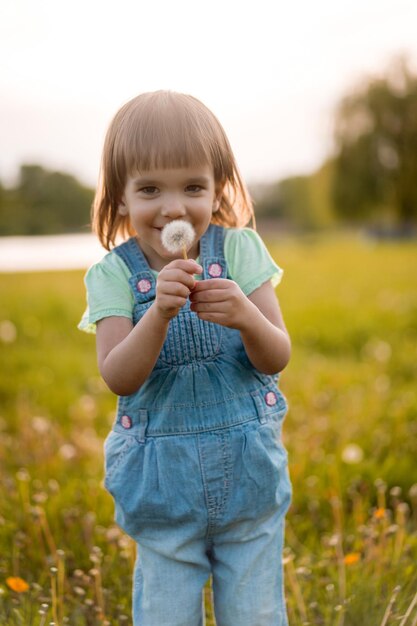 Bambina su un campo di tarassaco, al tramonto, bambino felice emotivo.