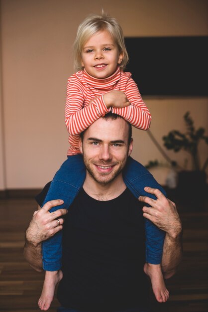 Bambina sulle spalle del padre con le braccia sulla sua testa