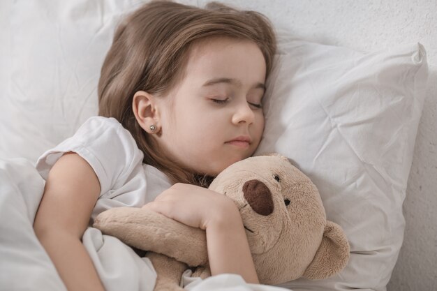 Bambina sveglia a letto con peluche.