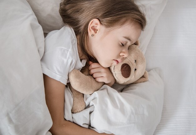 Bambina sveglia a letto con peluche.