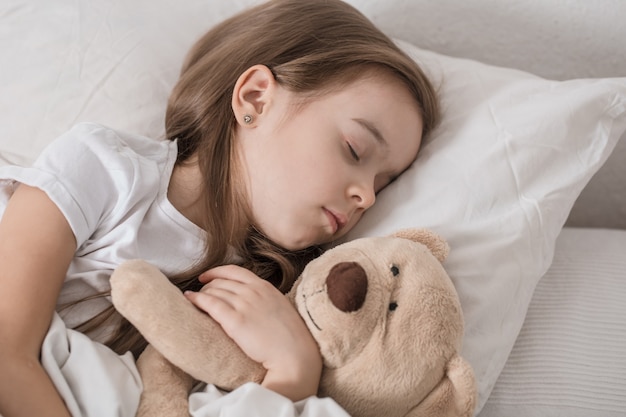 Bambina sveglia a letto con peluche.