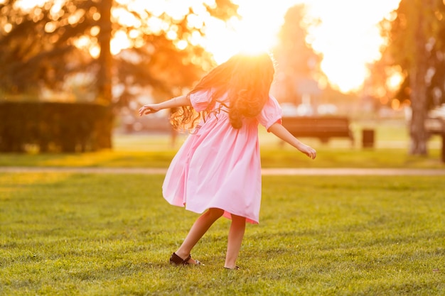 Bambina sveglia che cammina sull'erba al tramonto