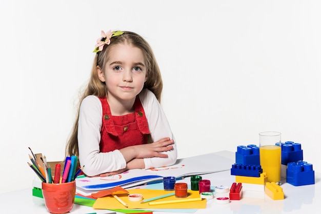 Bambina sveglia che disegna con vernice e pennello a casa