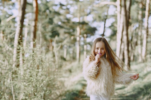 Bambina sveglia che gioca in una foresta di estate