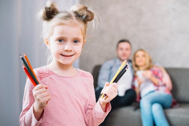 Bambina sveglia che mostra le matite variopinte del disegno