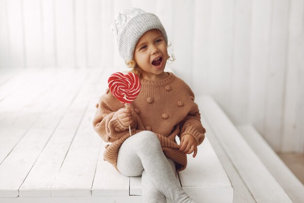 Bambina sveglia che si siede e che mangia caramella