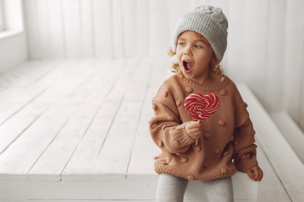 Bambina sveglia che si siede e che mangia caramella