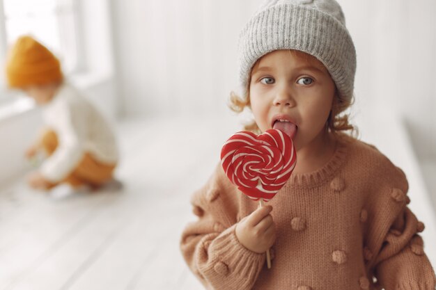 Bambina sveglia che si siede e che mangia caramella