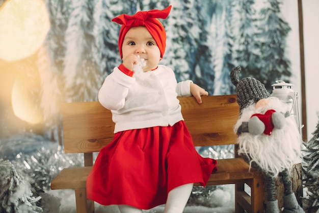 Bambina sveglia che si siede nelle decorazioni di un natale