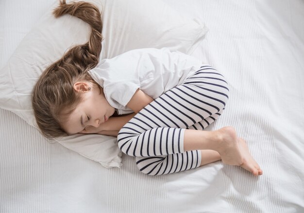 Bambina sveglia con capelli lunghi che dorme nel letto