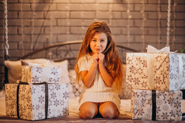 Bambina sveglia con i regali di Natale a letto