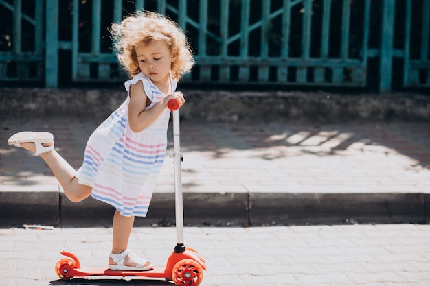 Bambina sveglia con il motorino di guida del parco riccio