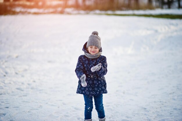 Bambina sveglia con le slitte del piattino all'aperto il giorno di inverno