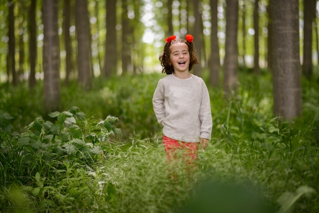 Bambina sveglia con quattro anni divertendosi in una foresta di pioppo