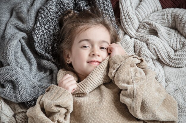 Bambina sveglia divertente in un maglione lavorato a maglia.