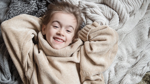 Bambina sveglia divertente in un maglione lavorato a maglia