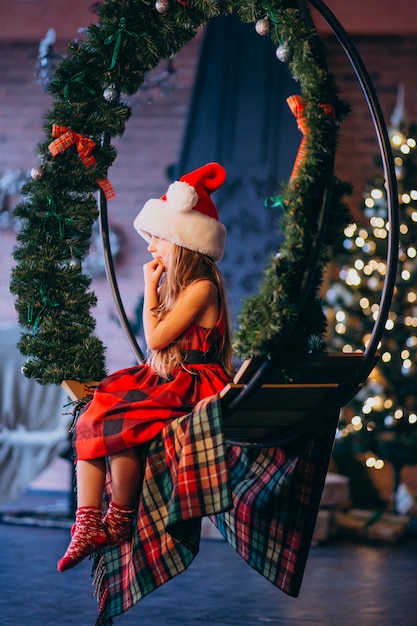 Bambina sveglia in cappello della santa e vestito rosso