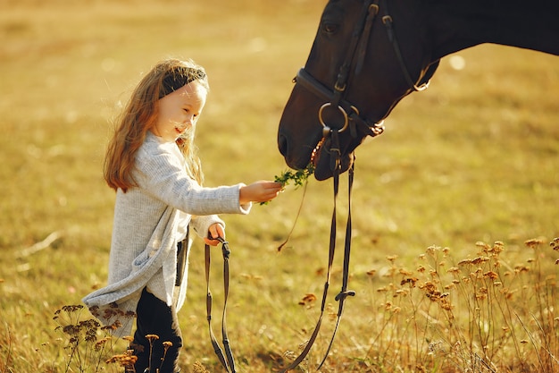 Bambina sveglia in un campo di autunno con il cavallo