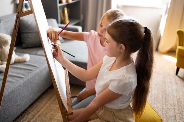 Bambine che disegnano usando il cavalletto a casa insieme