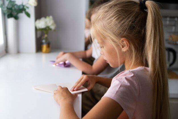 Bambine che giocano con la carta origami a casa