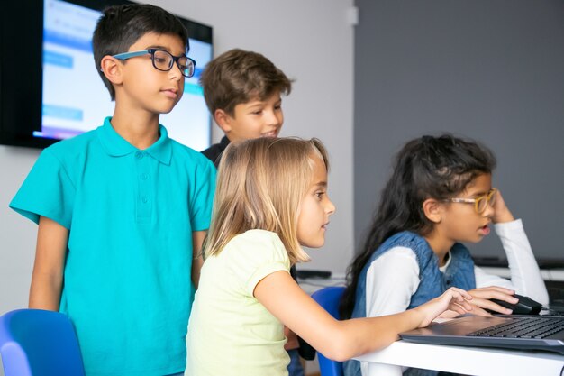 Bambine che usano laptop, studiano alla scuola di informatica e si siedono a tavola