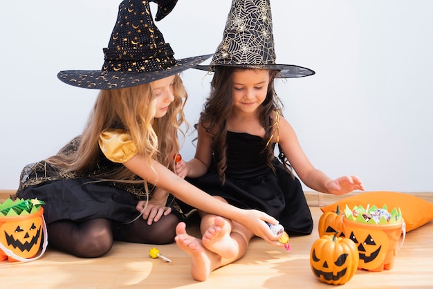 Bambine di vista frontale che si siedono sul pavimento su Halloween