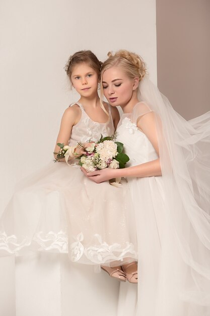 Bambine graziose con fiori vestiti in abiti da sposa