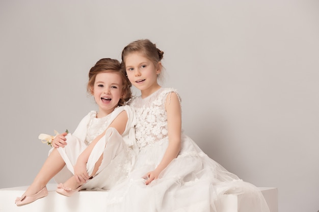 Bambine graziose con fiori vestiti in abiti da sposa.