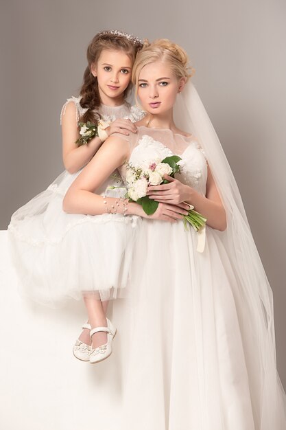 Bambine graziose con fiori vestiti in abiti da sposa