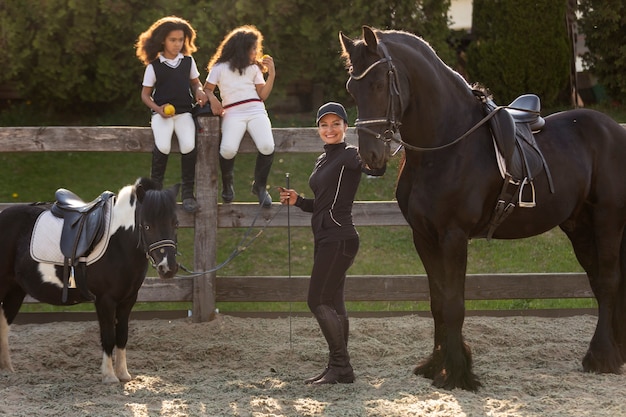 Bambini a figura intera che imparano a cavalcare