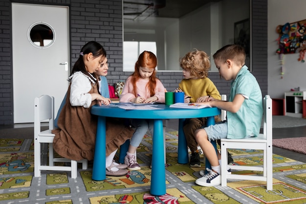 Bambini a tutto campo seduti insieme a tavola