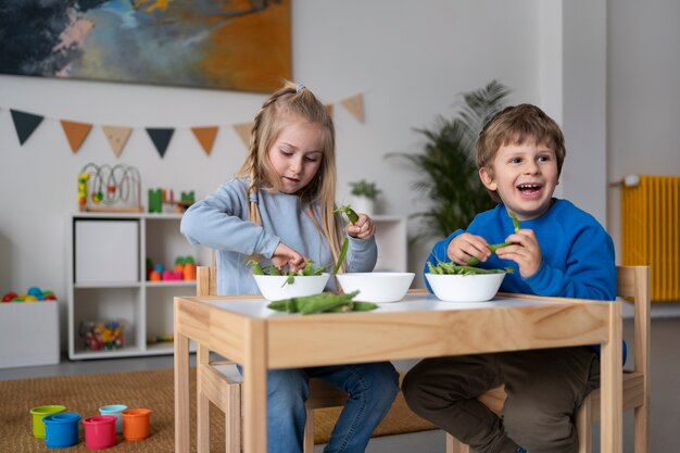 Bambini a tutto campo seduti insieme a tavola
