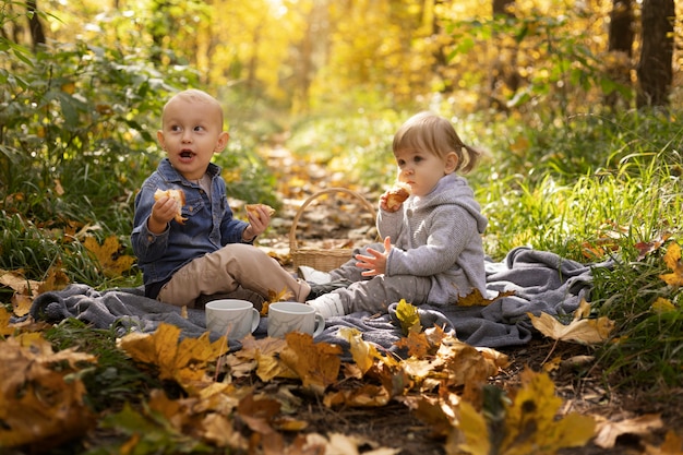 Bambini a tutto campo seduti su una coperta all'aperto